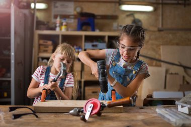 İki genç kız bir atölyede ahşap yapıyor