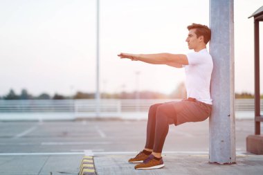 Genç adam dışarıda egzersiz yapıyor.