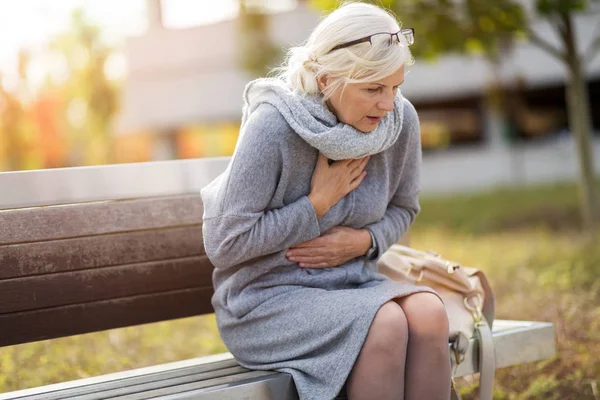 Senior Vrouw Lijden Aan Pijn Borst Tijdens Het Zitten Bank — Stockfoto