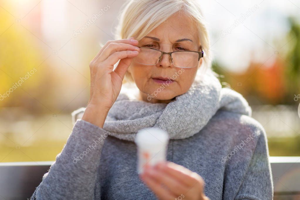 Senior woman taking prescription medicine outdoors