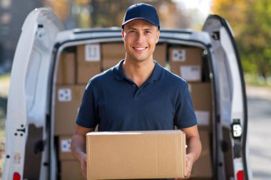 Delivery man standing in front of his van clipart