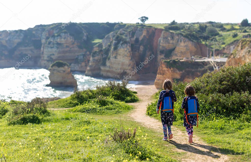 Two young girls exploring Portuguese coastline Praia Dona Ana, Lagos, Algarve, Portugal 
