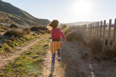 Little girl running through the Spanish landscape, Rambla del Playazo, Cabo de Gata - Nijar Natural Park, Spain clipart