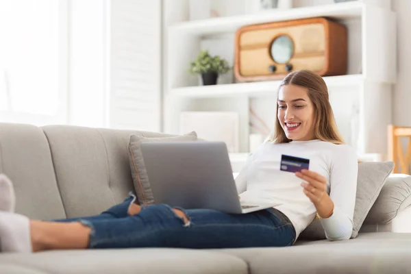 Woman on couch with credit card and laptop
