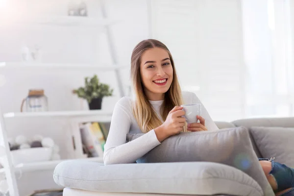 一个年轻女子坐在沙发上喝咖啡的肖像 — 图库照片