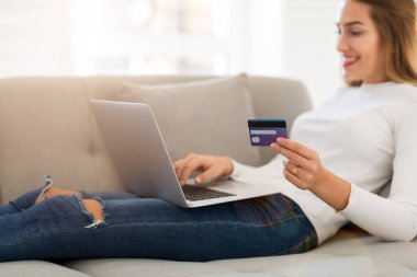 Kadın kanepede kredi kartı ve dizüstü bilgisayar ile