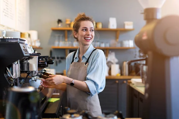 彼女のカフェカウンターで顧客のためのコーヒーを準備若いバリスタ — ストック写真