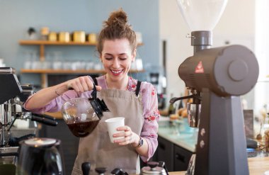 Genç barista onu kafe sayaç müşteriler için kahve hazırlamak