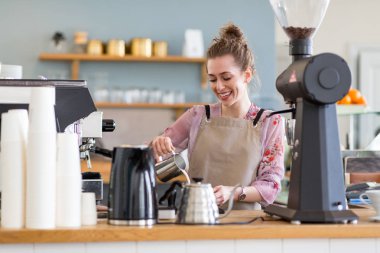 Genç barista onu kafe sayaç müşteriler için kahve hazırlamak