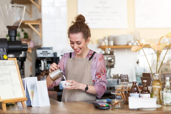 年轻的咖啡师在她的咖啡店为顾客准备咖啡 — 图库照片
