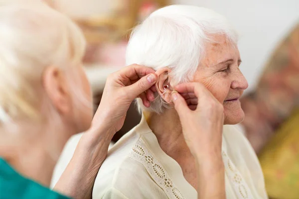 Female Doctor Applying Hearing Aid Senior Woman Ear — Stock Photo, Image