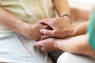 Hemşire ellerini tutarak yaşlı hasta teselli