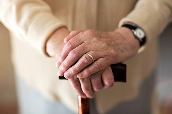 Close-up of senior's hands leaning on walking cane
