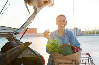 Otoparkta alışveriş yapan genç bir kadın.