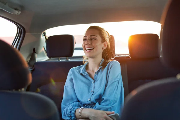 Arabanın Arka Koltuğunda Akıllı Telefonu Olan Genç Bir Kadın — Stok fotoğraf