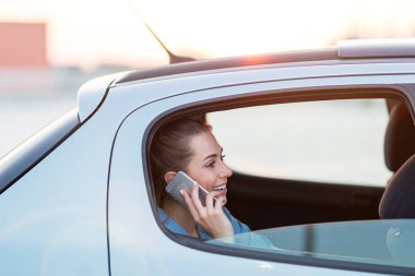 Arabanın arka koltuğunda akıllı telefonu olan genç bir kadın.