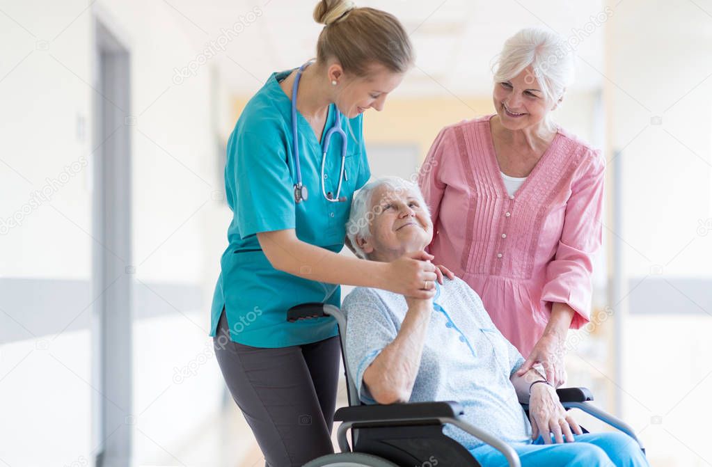 Elderly woman on wheelchair with her daughter and nurse