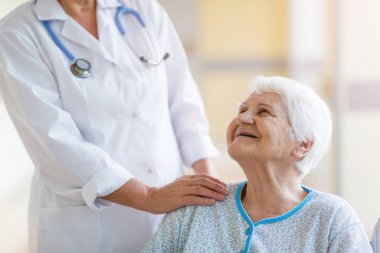 Hastanede doktor ile tekerlekli sandalyede yaşlı kadın