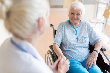 Hastanede doktor ile tekerlekli sandalyede yaşlı kadın