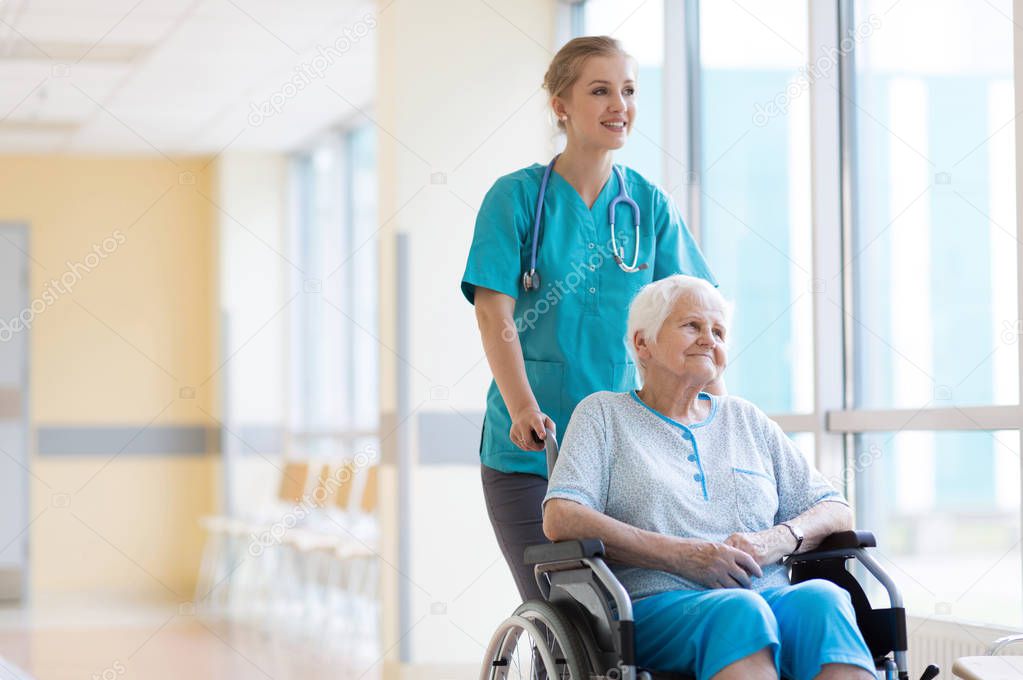 Senior woman in wheelchair with nurse in hospital