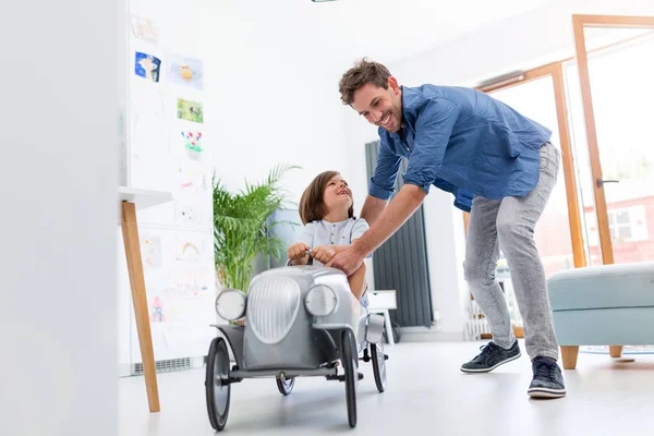 Father helping his son to drive a toy peddle car