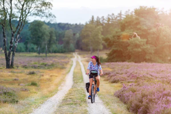 Young woman riding bicycle in the countryside, Hoge Veluwe, Holland