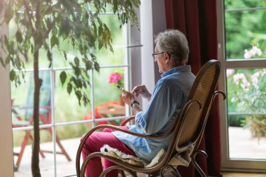 Evde cep telefonu kullanan kıdemli adam.