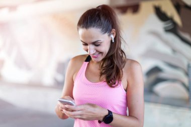 Bir şehir bölgesinde akıllı telefon kullanan kadın koşucu