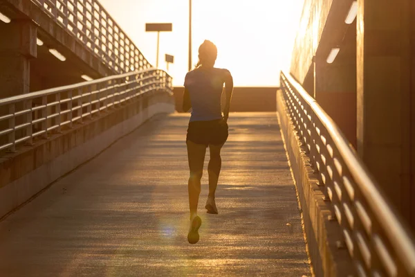 Genç kadın gün batımında şehirde park düzeyinde çalışan