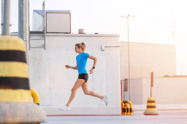 Genç kadın gün batımında şehirde park düzeyinde çalışan