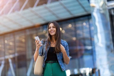 Şehirde akıllı telefon ve kahve ile genç kadın 
