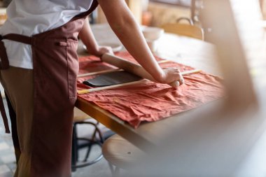 Kadın çömlek sanatçısı kilden seramik yapıyor.