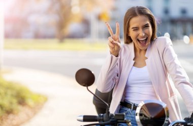 Mutlu genç bir kadın scooter 'a biniyor.