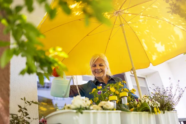 バルコニーで彼女の植物の世話をするシニア女性 — ストック写真
