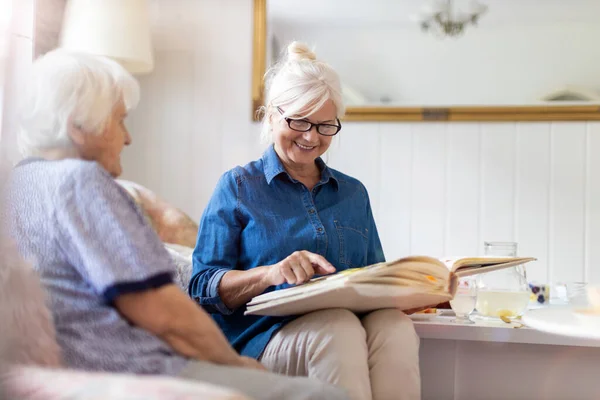 Seniorin Und Ihre Erwachsene Tochter Betrachten Gemeinsam Fotoalbum Auf Couch — Stockfoto