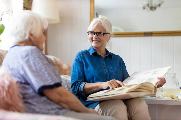 Seniorin Und Ihre Erwachsene Tochter Betrachten Gemeinsam Fotoalbum Auf Couch — Stockfoto