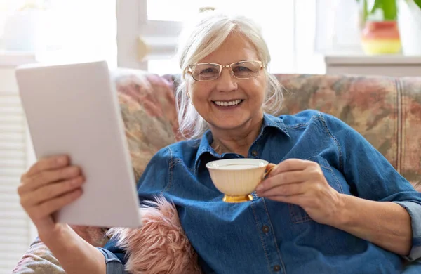 家中使用数码平板电脑的老年妇女 免版税图库图片