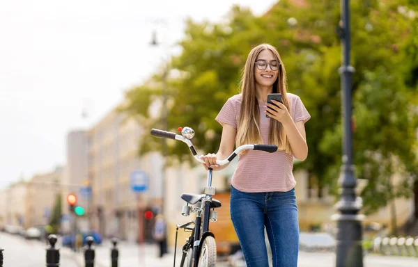 Şehirde Bisiklet Sürerken Akıllı Telefon Kullanan Çekici Genç Bir Kadın — Stok fotoğraf