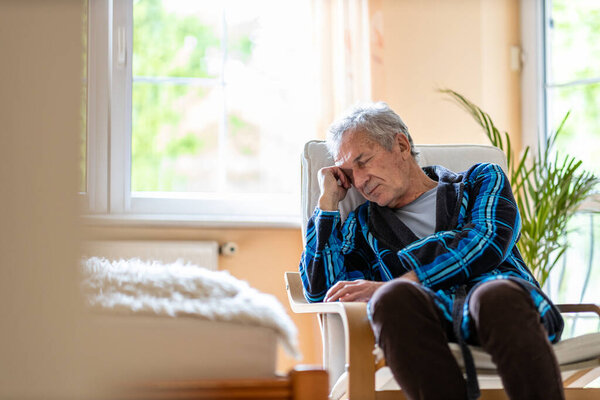 Пожилой человек выглядит грустным дома
