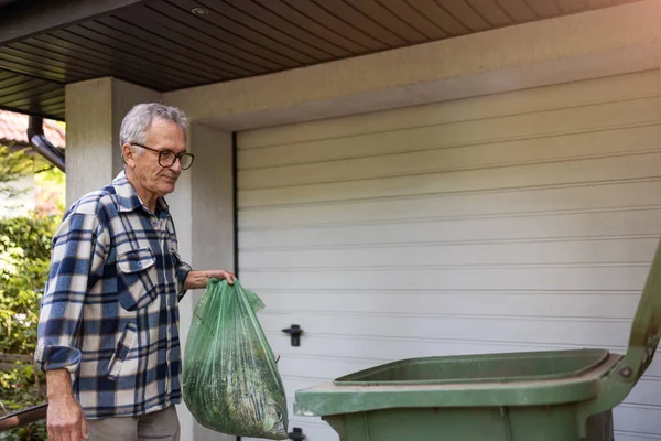 Senior man taking out garbage