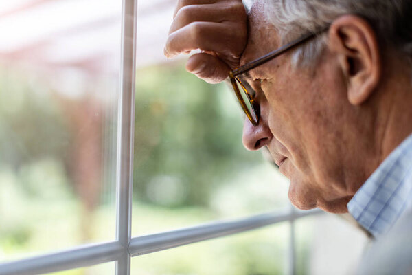 Senior man looking out of window at home