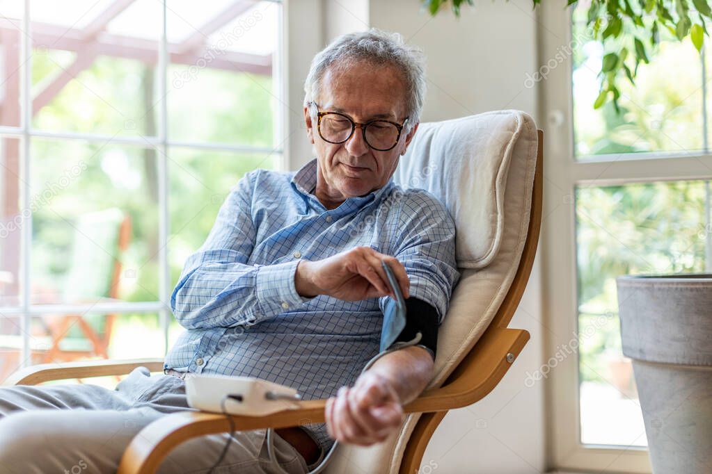 Senior man using medical device to measure blood pressure
