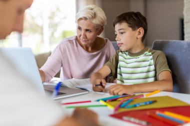 Anne, çocuklarına ev ödevlerinde yardım ediyor.