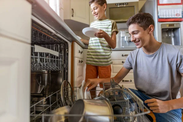 Два Мальчика Загружают Посудомоечную Машину Вместе Дома — стоковое фото
