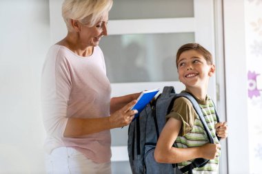 Mother and son with backpack in entrance hall clipart
