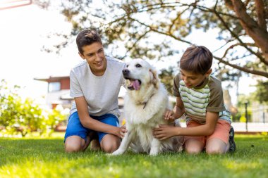 Bahçede köpekleriyle oynayan iki çocuk.