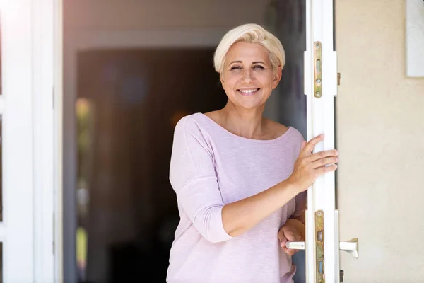 Smilende Kvinne Som Står Døren Til Sitt Hus – stockfoto