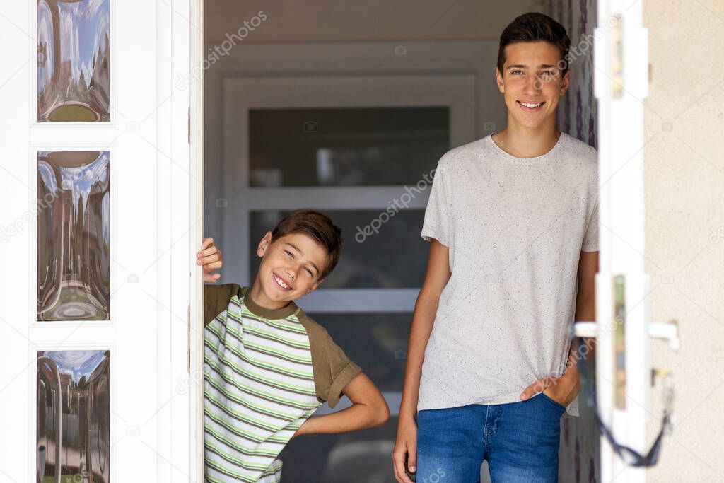 Two brothers standing in doorway of their house