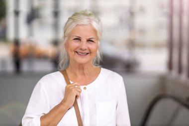 Şehirde gülümseyen yaşlı kadının portresi.