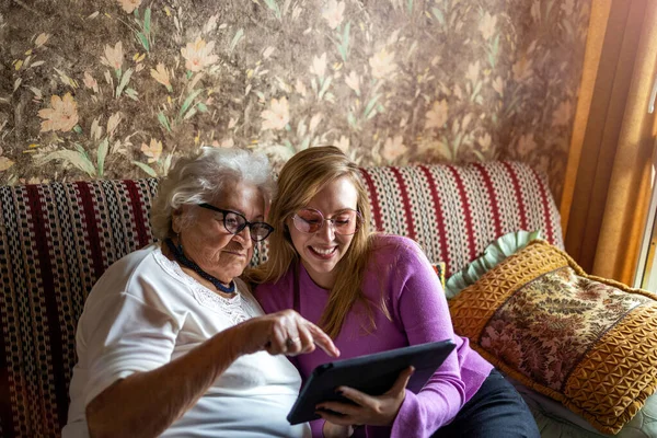한연로 부인과 손녀가 태블릿을 소파에 — 스톡 사진